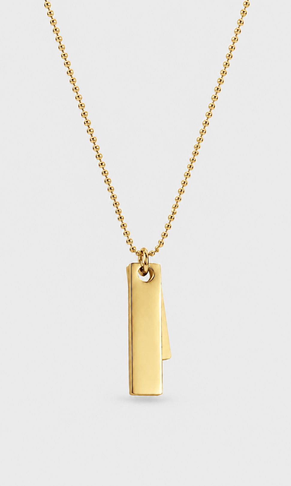 A gold ball chain necklace with a minimalist, double-layered vertical rectangular bar pendant, shown against a light gray background.