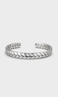 A silver-toned metal cuff bracelet with a textured, woven leaf-like pattern, displayed on a light gray background.
