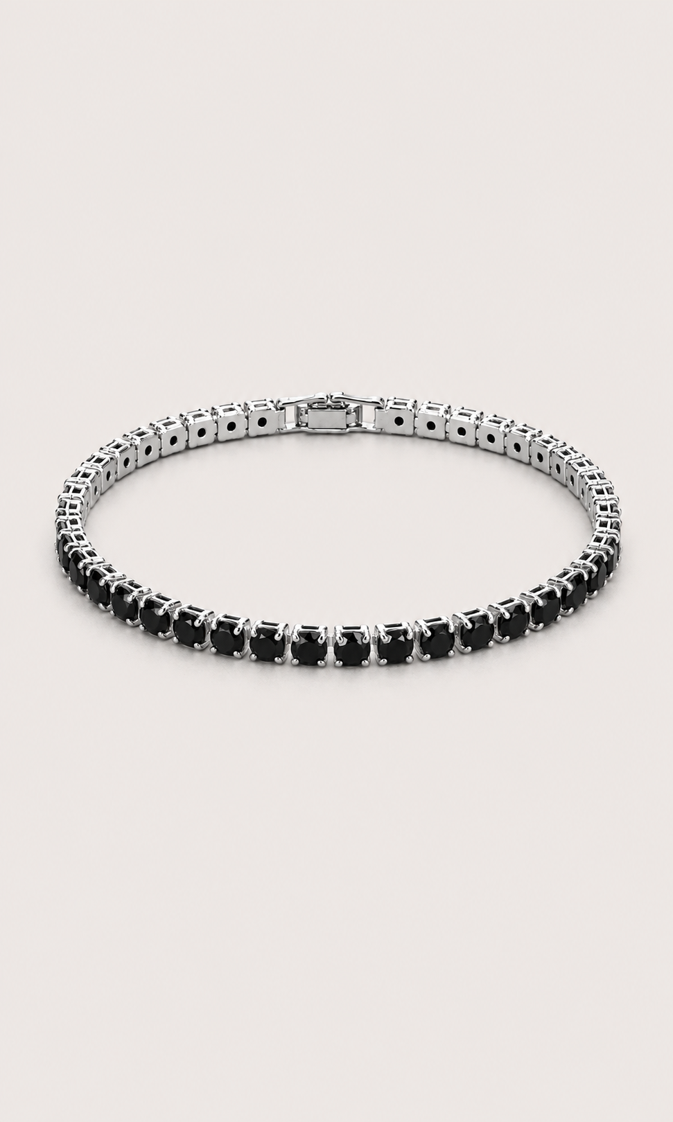 A tennis-style bracelet with round black gemstones in a silver-toned setting, arranged in a circular shape on a light beige background.