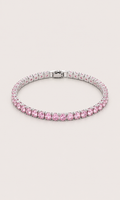 A tennis bracelet featuring round pink gemstones in a silver-toned setting, displayed on a light beige background.