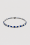 A tennis bracelet featuring alternating rows of deep blue sapphires and clear cubic zirconia stones in a silver-toned setting, displayed on a light gray background.