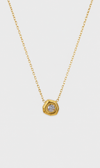 A gold chain necklace with a hexagonal pendant featuring a clear round gemstone, shown against a light gray background.