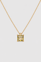 A gold chain necklace with a small square yellow gemstone pendant, displayed against a light gray background.