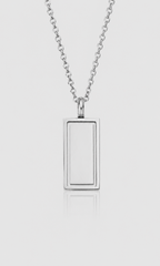 A silver-toned rectangular pendant necklace with a smooth, polished finish, suspended from a matching chain against a light gray background.