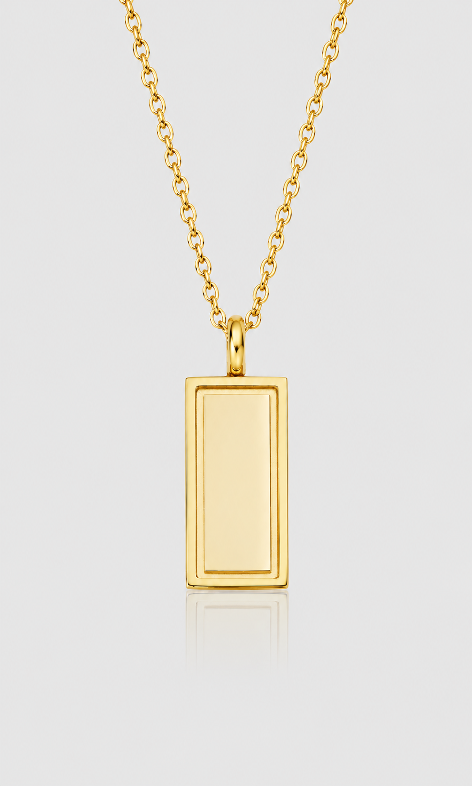 A gold rectangular pendant necklace with a smooth, polished finish, suspended from a matching gold chain against a light gray background.