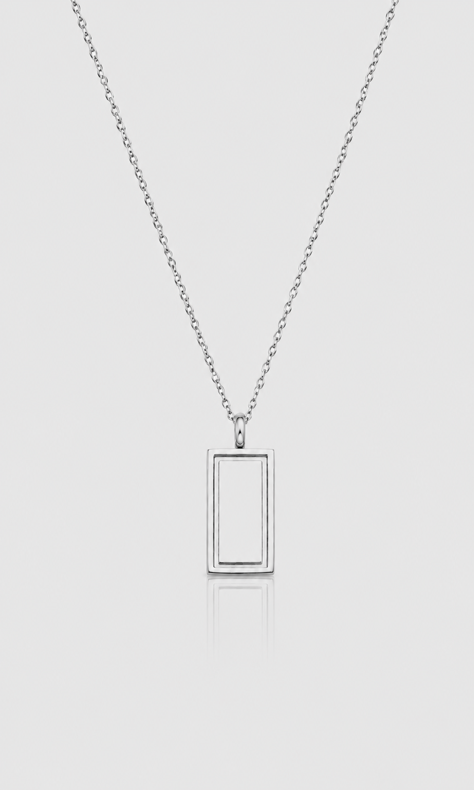 A silver-toned necklace with a minimalist rectangular frame pendant, suspended on a delicate chain against a light gray background.