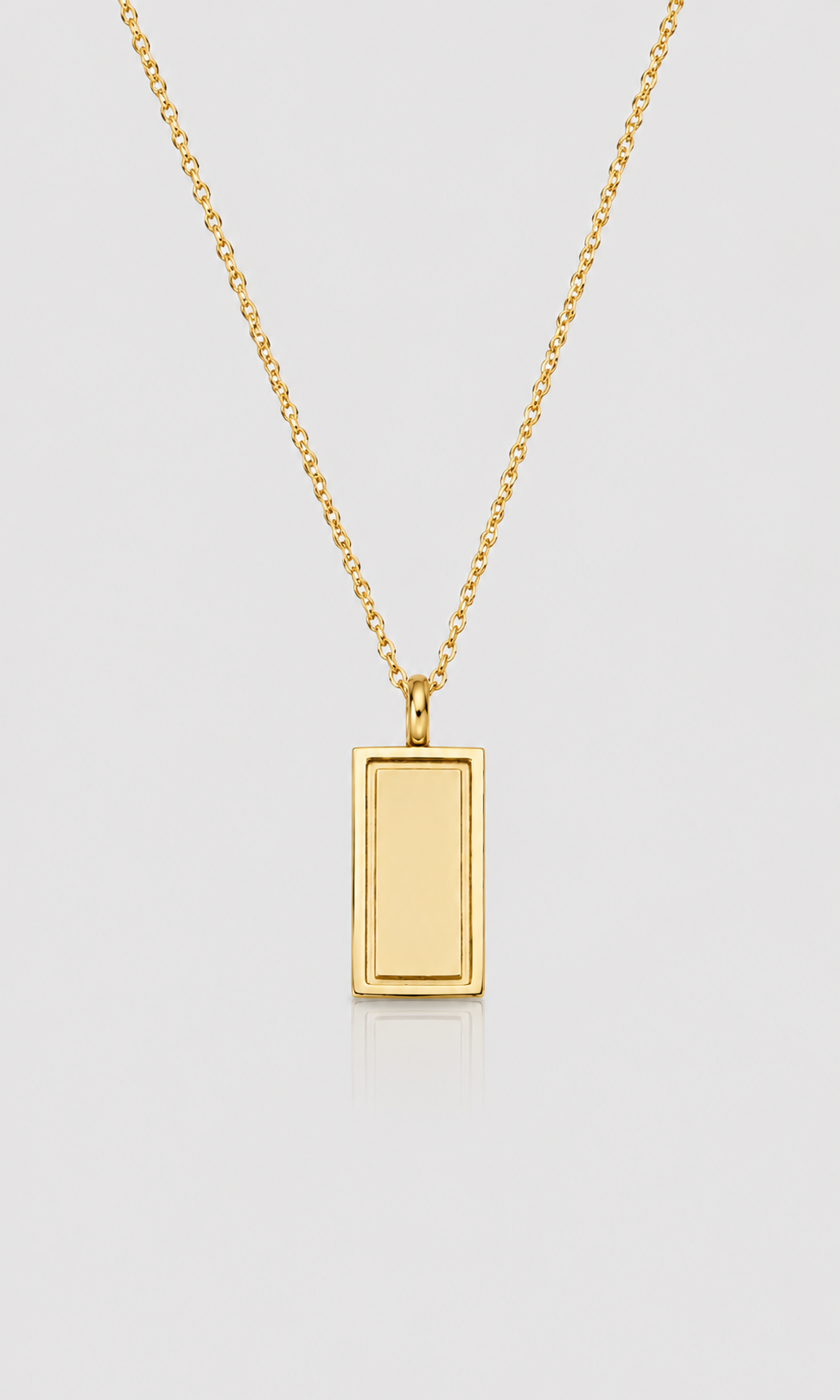 A gold rectangular pendant necklace with a smooth, polished finish on a delicate gold chain, presented on a light gray background.