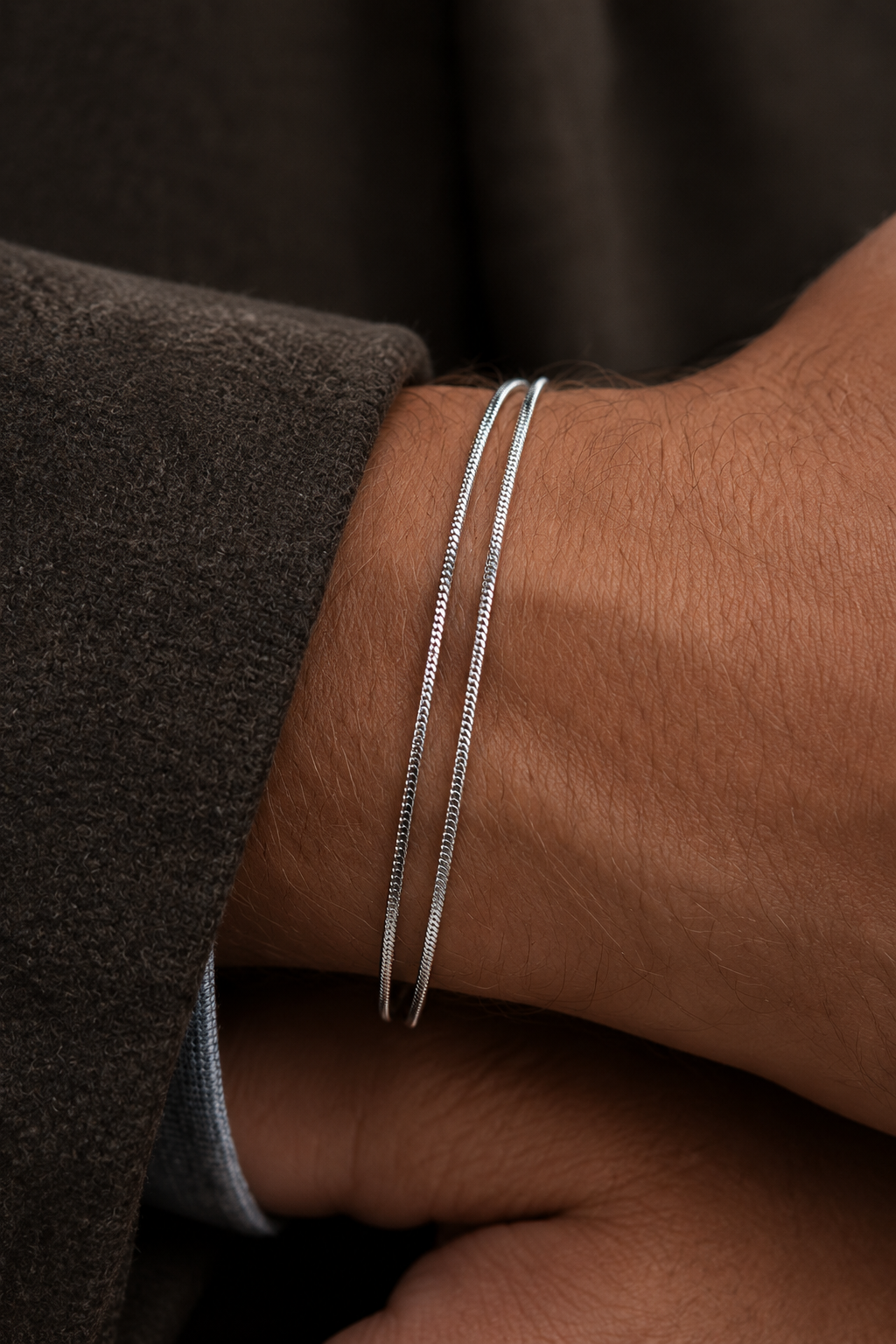 A silver snake chain necklace with a small rectangular metal tag engraved with the brand name 'ANEESA ATELIER', displayed on a light gray background.