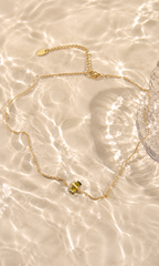 A delicate gold chain necklace with a small gold bow charm, 