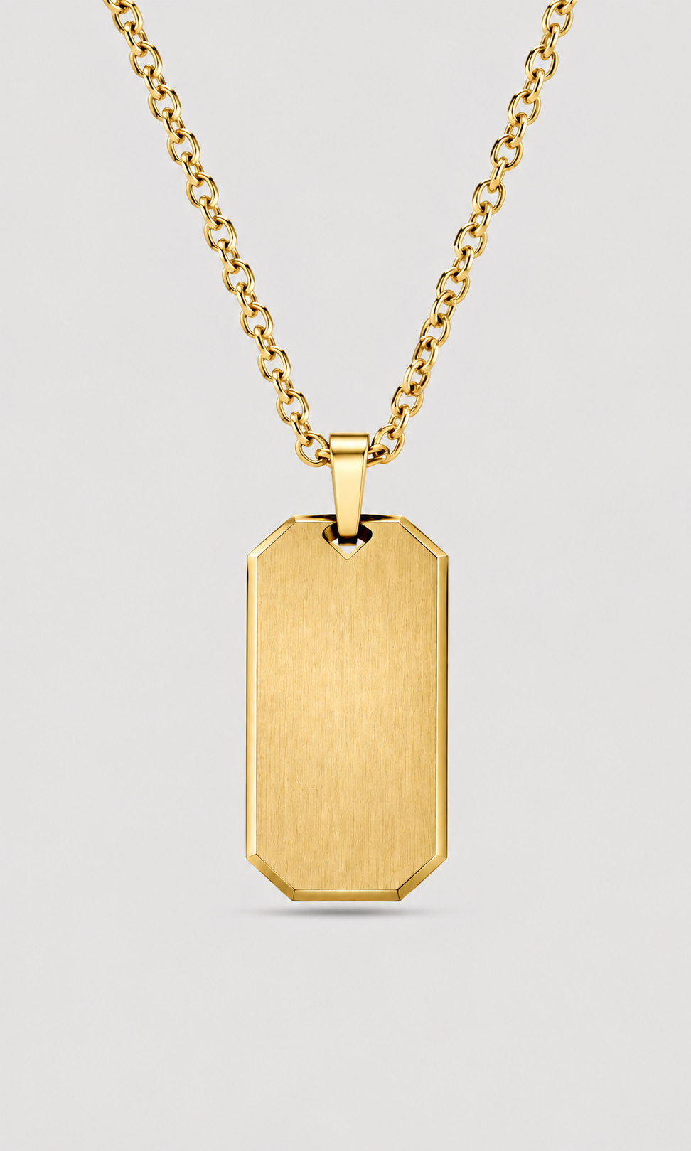 A gold dog tag pendant necklace with a brushed finish, suspended from a gold link chain against a light gray background.