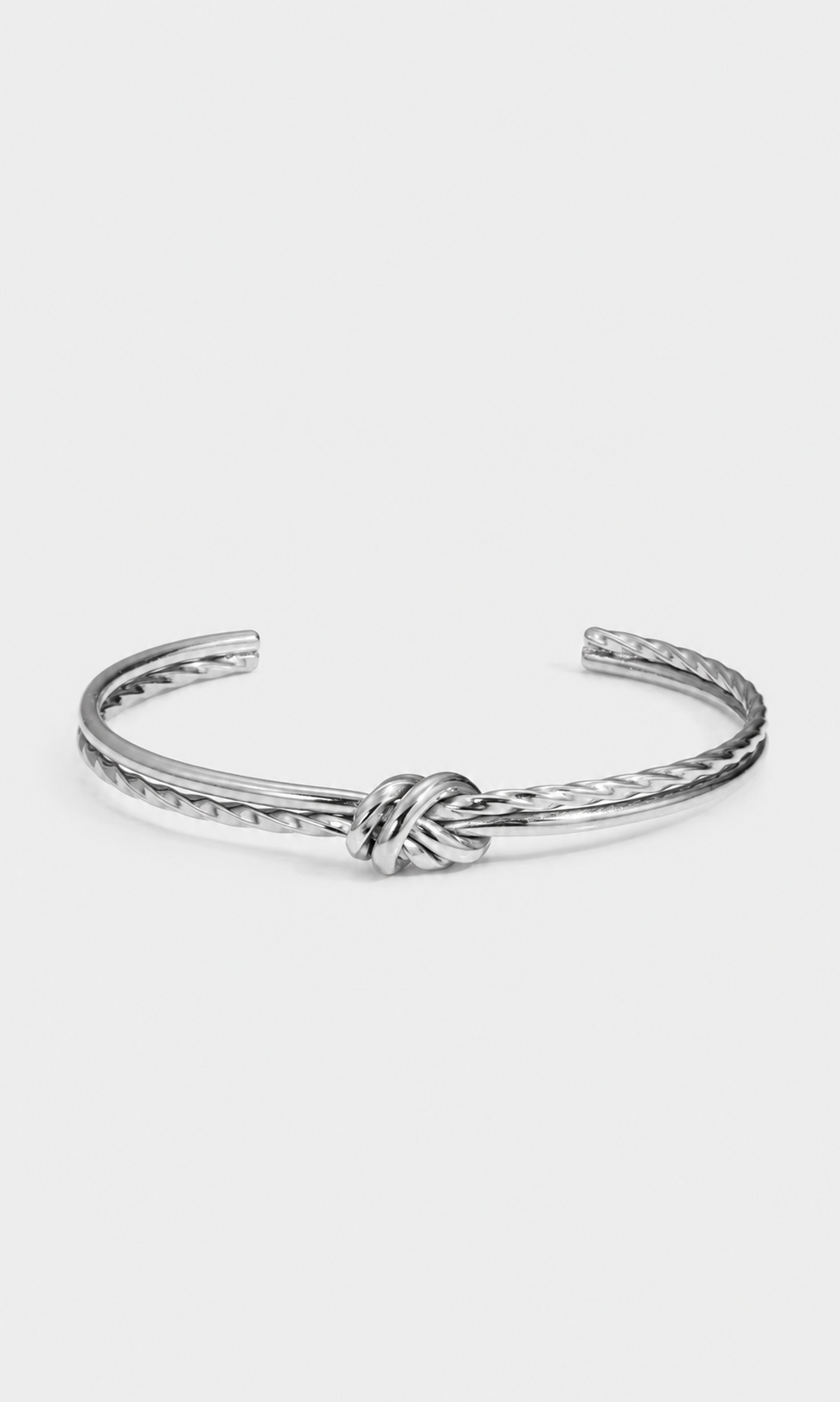 A silver-toned metal cuff bracelet featuring a central knotted detail and textured twisted edges, displayed on a clean, light gray background.